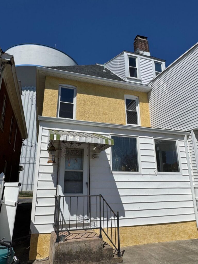 Back of a home with a yellow stucco upper wall and stucco foundation