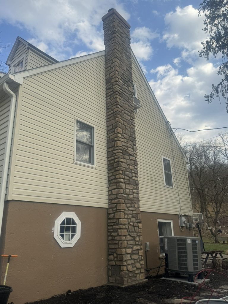 Stacked stone veneer chimney running up the side of a two-story home