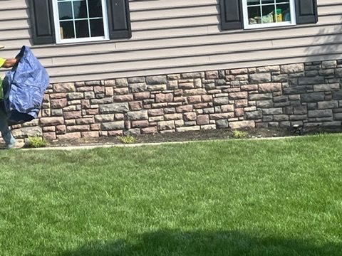 Stone veneer along the foundation of a vinyl-sided home