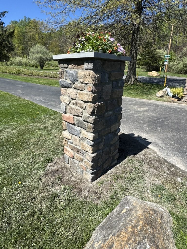 Stone veneer pillar with a bluestone cap and planter at the end of a driveway